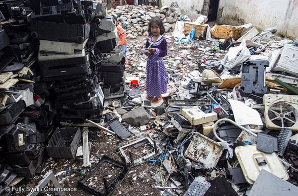 A child standing on top of and surrounded by various electronic debris