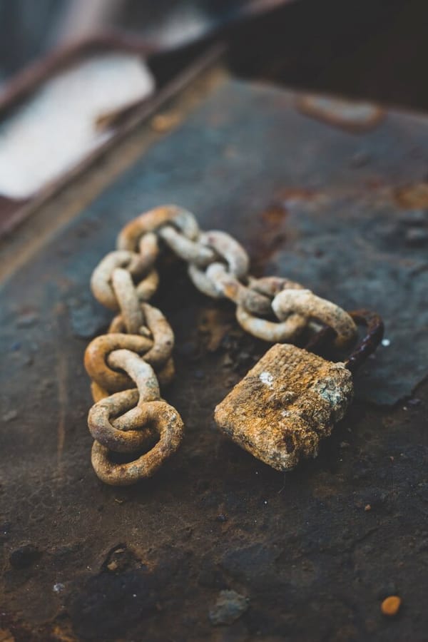 A rusted chain and lock on a rusted metal surface